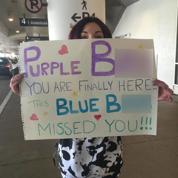 Person holding a creative and colorful airport pickup sign with playful text, making everyone chuckle.