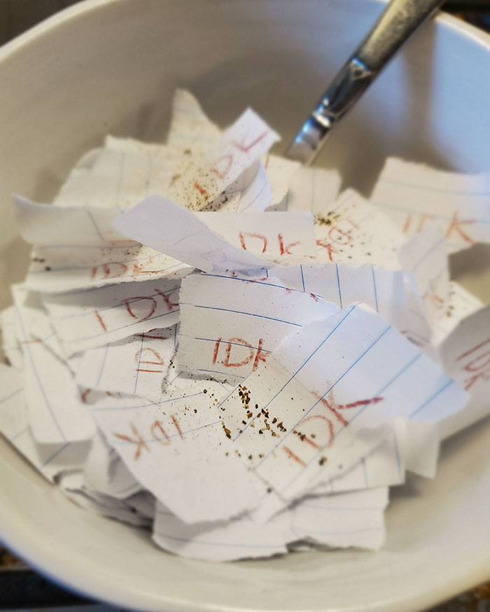 Bowl filled with torn paper notes, each reading "IDK" in red, reflecting a parent's humorous take on decision-making.