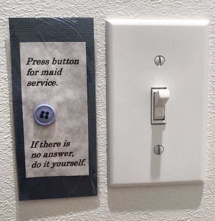 Light switch humor with a mock maid service button note on the wall, showcasing creative parents' humor.