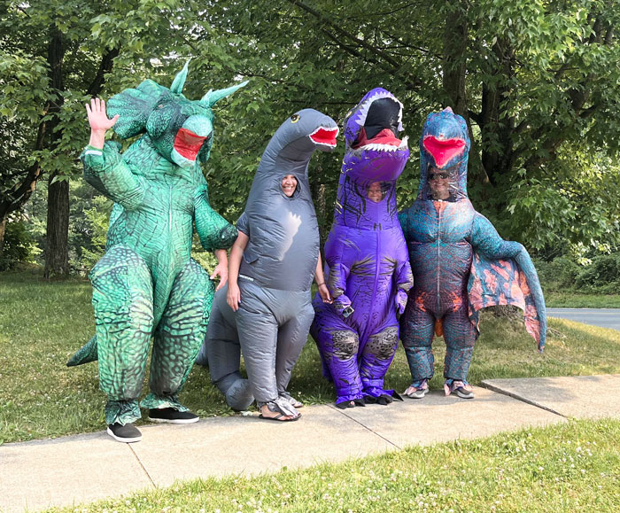 Parents with a great sense of humor in dinosaur costumes posing outdoors.
