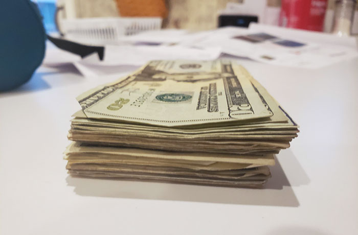 Stack of US dollars on a table showing a parent's humor in surprising their kids.