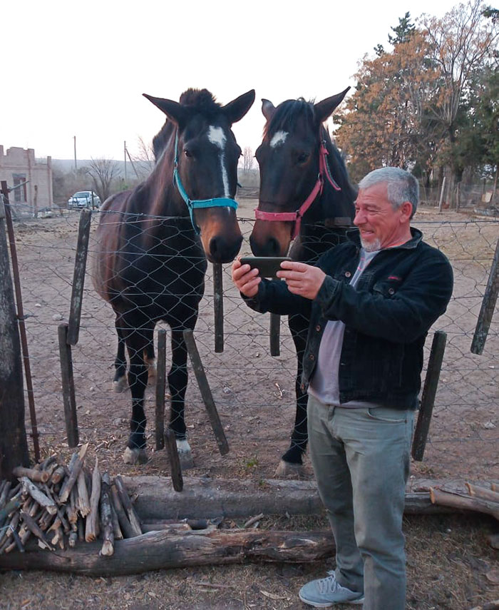 Man humorously taking a selfie with two horses behind a fence, showcasing parent humor.