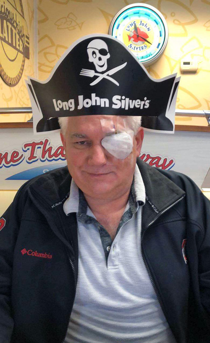 Man with humorous pirate hat in restaurant, showcasing a parent's fun sense of humor.
