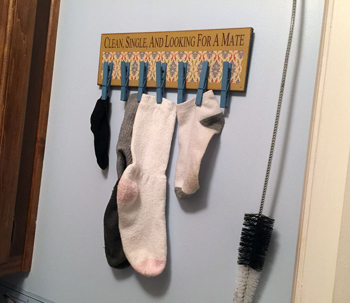 Socks hung under a humorous sign, showcasing a parent's wit in organizing with style.