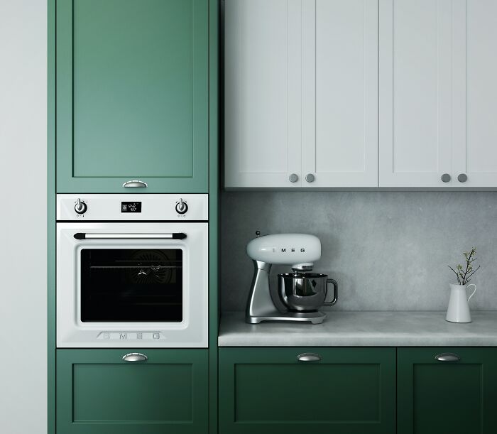Green kitchen cabinets paired with white upper cabinets in a modern kitchen featuring a silver mixer and built-in oven.