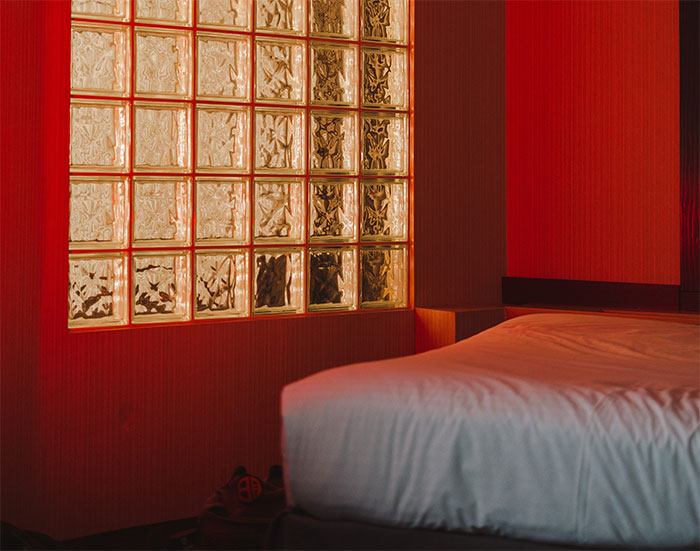 Dark red room with a bed and glass panels highlighting a happy color to transform your home and bring joy.