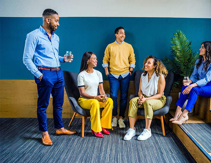 A group of five people talking and sitting in a blue room showcasing happy color ideas to transform your home.