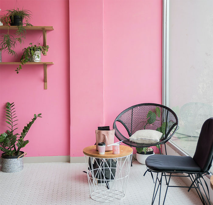 Bright pink room with black chairs and table, showcasing a happy color that can transform your home and bring joy.