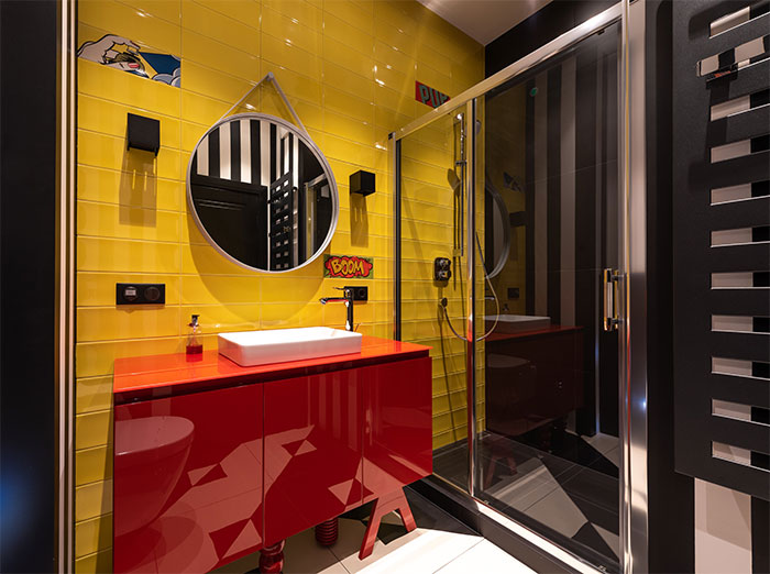 Bathroom featuring glossy bright yellow tiles and a red cabinet showcasing a happy color to transform your home.