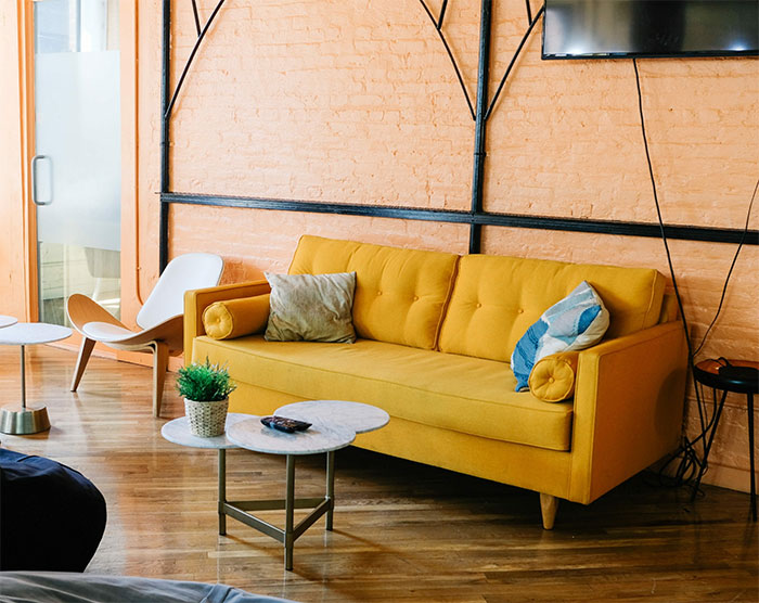 Peach room featuring a bright yellow sofa and colorful pillows, showcasing a happy color that transforms home joyfully.