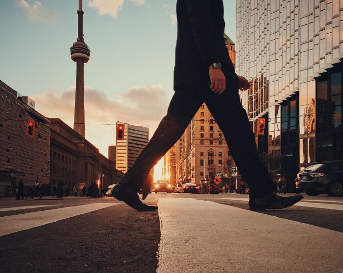 Man in suit walking downtown during sunset, testing wits of the busy city's rhythm.