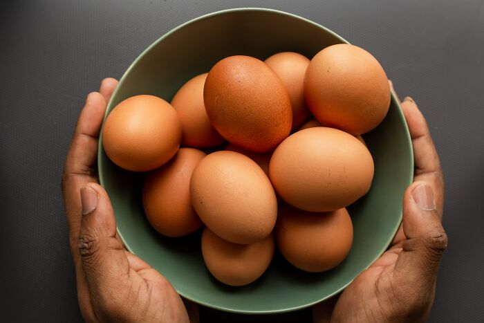 Person holding a bowl of brown eggs, representing a clever solution to a tough riddle.