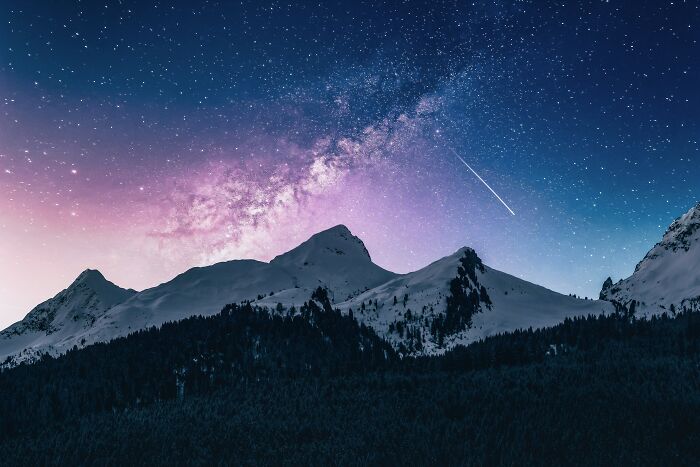 Snowy mountain under a starry sky, showcasing the dazzling night sky above.