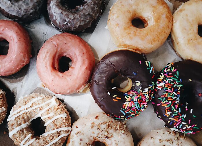 A pile of assorted donuts with colorful toppings, arranged closely together to test your wits in choosing a favorite.