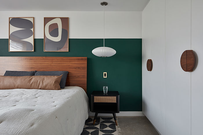 Bedroom with green and white walls featuring abstract paintings and modern furniture, showcasing expert-approved home designs.
