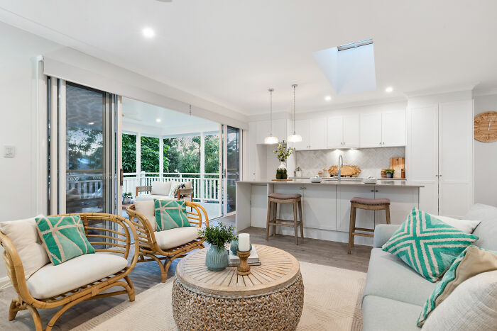Bright open room featuring white kitchen, gray sofa, and wooden table with chairs showcasing expert-approved home design ideas.