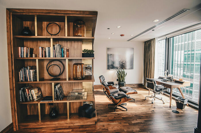 Room featuring a brown bookshelf, modern table with chairs near window, showcasing expert-approved interior design ideas.