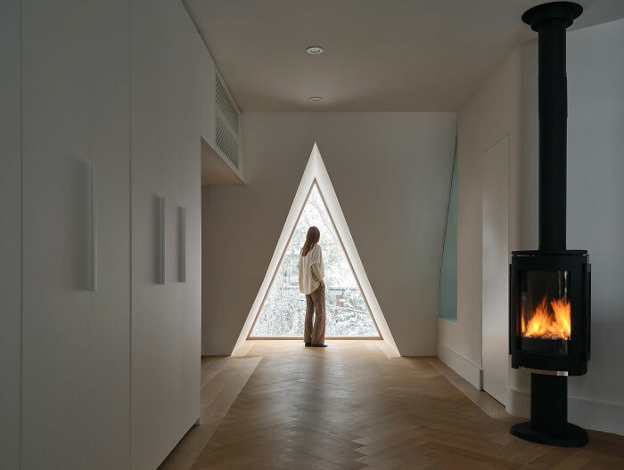 Woman looking through a triangular window in a modern home showcasing expert-approved interior design ideas.