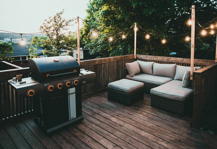 Black gas grill and cozy outdoor seating on a brown wooden deck featuring expert-approved home design ideas.