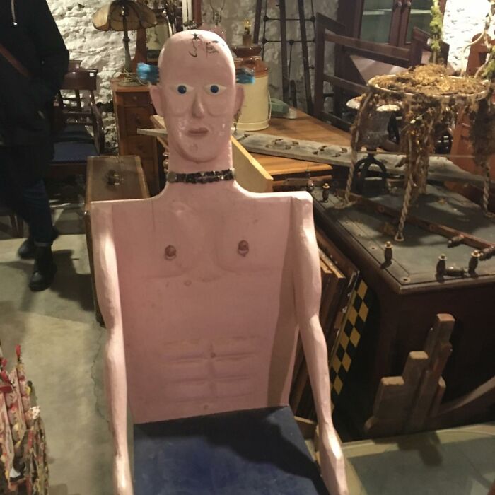 Unusual thrift store donation featuring a quirky handmade mannequin chair with exaggerated human features.