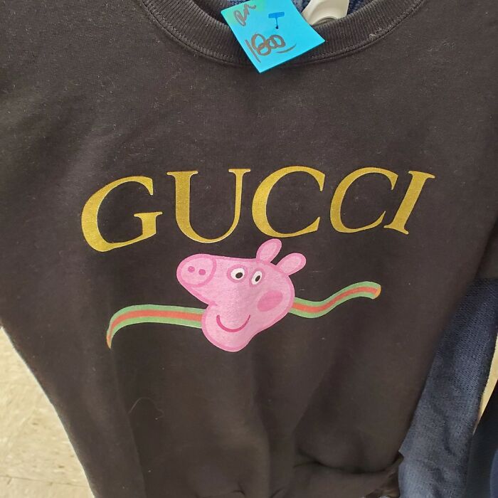Black sweatshirt with a spoof Gucci logo and cartoon pig face, one of the weird thrift store donations featured on Instagram.