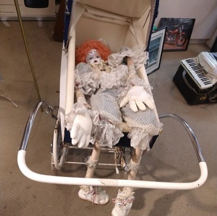 Creepy vintage clown doll lying in an old-fashioned baby stroller, one of the weird items donated to thrift stores.