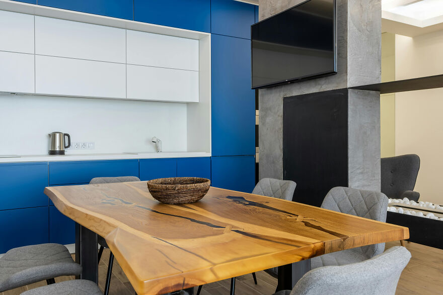 Large wooden table in a modern kitchen featuring stylish white and dark blue kitchen cabinets with seating.