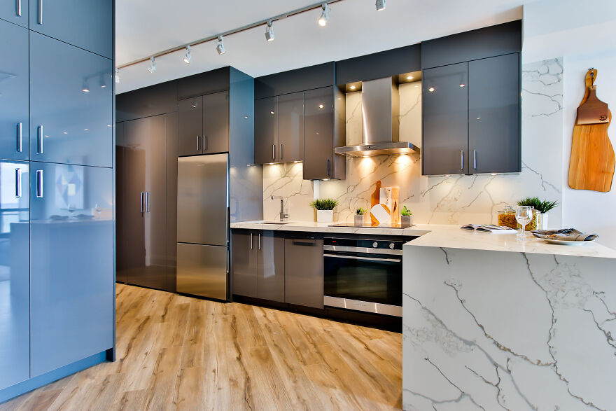Blue and gray modern kitchen cabinets with stainless steel appliances and marble countertops in a stylish kitchen design.
