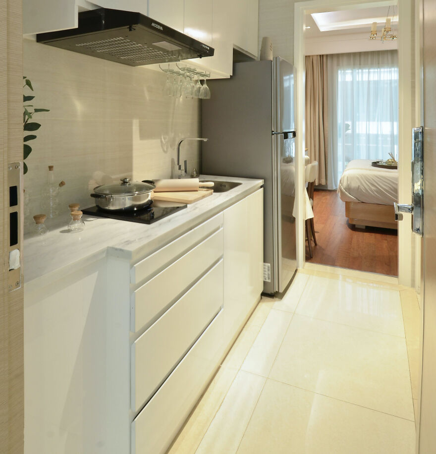 White kitchen featuring modern vertical lower kitchen cabinets, sleek countertop, and stainless steel appliances in a bright space.