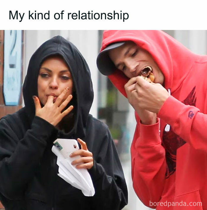 Couple in hoodies enjoys food together, capturing a funny meme moment for couples.