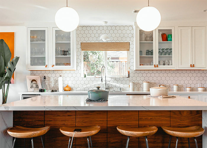 White kitchen with white marble countertops and wooden table White kitchen with white marble countertops and wooden table