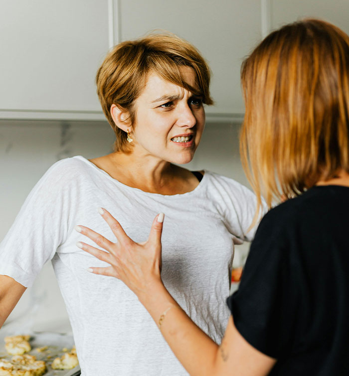 Two women arguing indoors, one refusing to change her daughter&rsquo;s dress, causing conflict with an entitled mom.