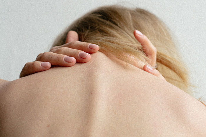 Person with hands grasping the back of their neck, conveying tension and unease related to creepy facts about the world.
