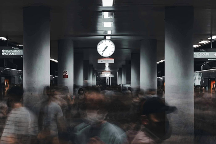 Blurred crowd moving through a dimly lit underground station with a clock overhead, evoking creepy facts about the world.