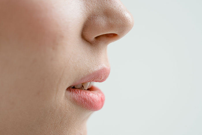 Close-up of a person's lips and nose with clear skin highlighting subtle textures for creepy facts about the world concept.