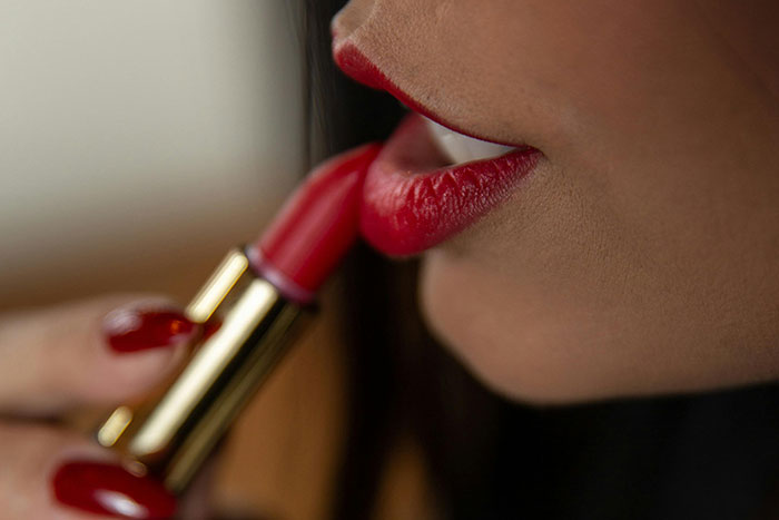 Close-up of a woman applying red lipstick, illustrating creepy facts about the world and unexpected beauty secrets.