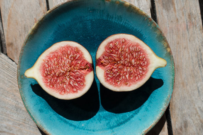 Two fig halves on a blue plate on wooden surface, illustrating creepy facts about the world through natural imagery.