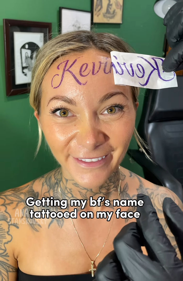 Influencer with fake tattoo of boyfriend's name on forehead in a tattoo studio setting.