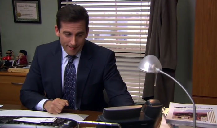 Michael Scott happy sitting on the desk 