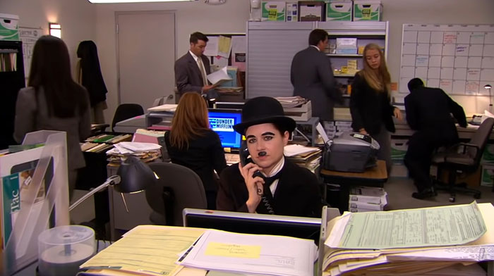 Pam Beesley dressed as Charlie Chaplin talking on phone 
