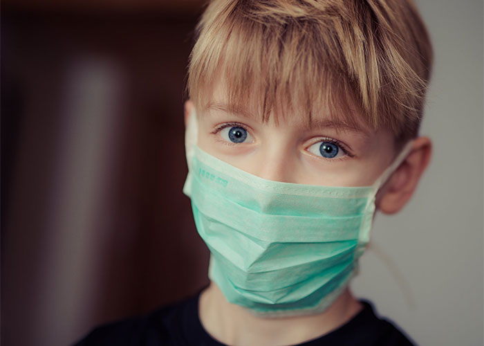 Young boy wearing a teal face mask indoors, representing lesser-known frugal tips with the biggest impact concept.