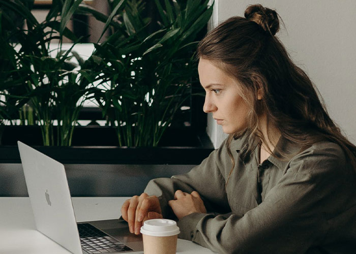 Young woman focused on laptop screen in a cozy workspace, exploring lesser-known frugal tips with big impact.