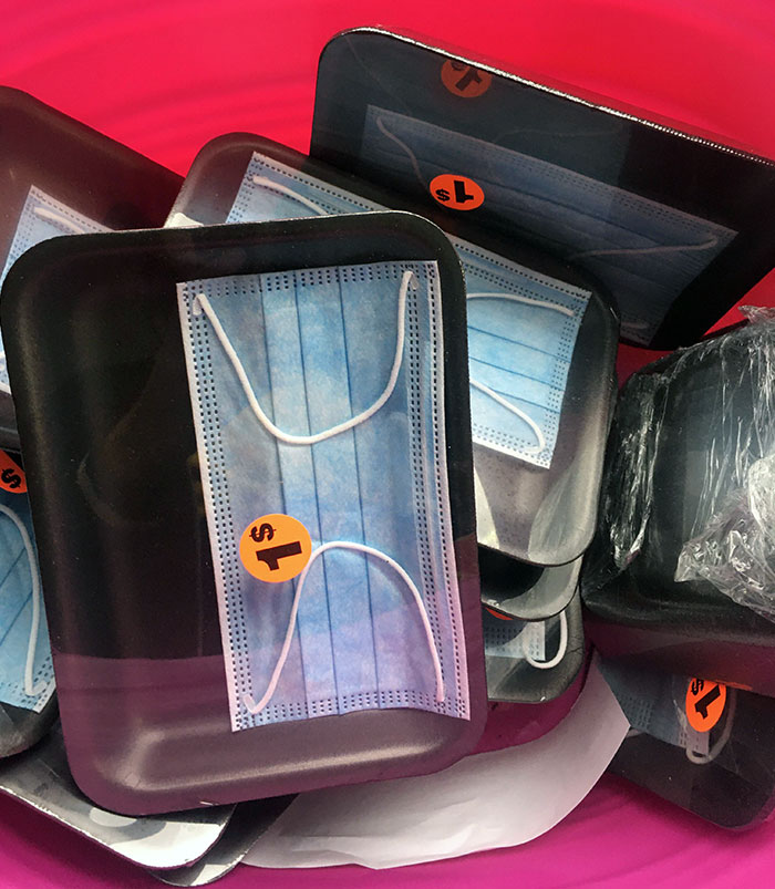 Black trays packaging individual face masks with a $1 price sticker, showcasing a facepalm-worthy packaging fail.