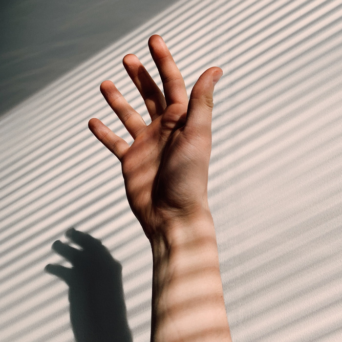 Left hand raised with fingers spread against wall shadows, illustrating unusual details for weird Guinness World Records.