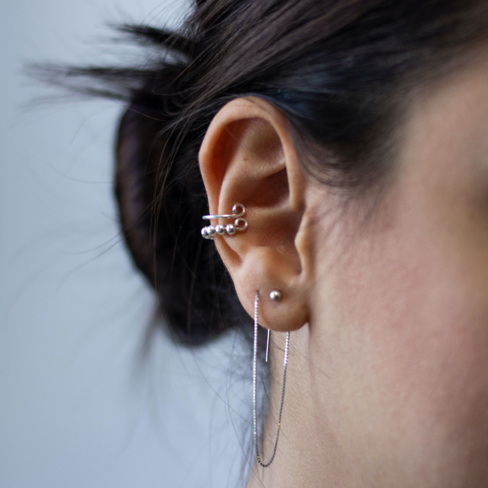 Close-up of a pierced ear with multiple silver earrings, representing unique Guinness World Records for unusual body modifications.