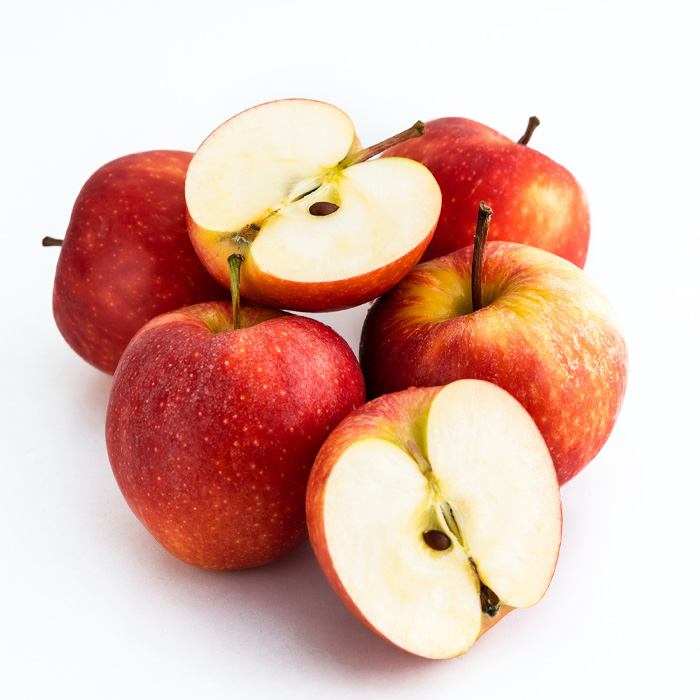 Red apples cut in half and whole arranged on a white surface representing weirdest Guinness World Records fruit.