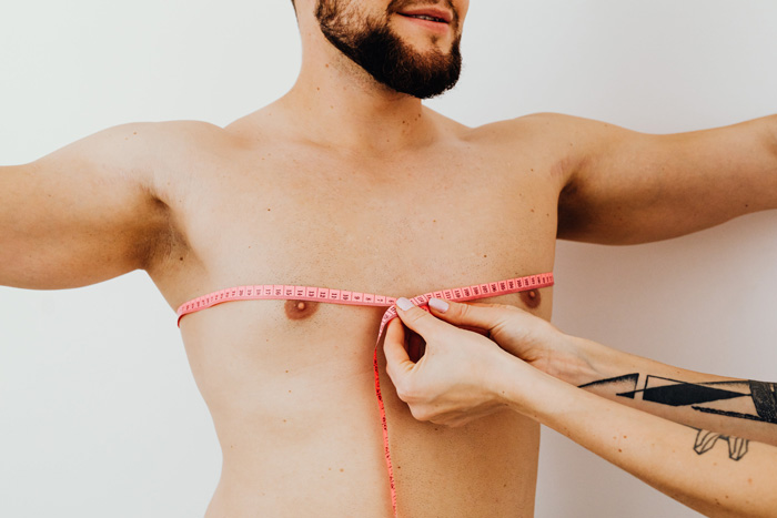 Measuring a man's chest with a pink tape, relating to weird Guinness World Records involving chest measurement.