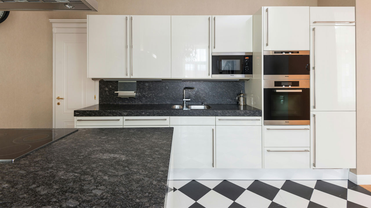 White kitchen cabinets with sleek black countertops and stainless steel appliances in a modern cooking space. White kitchen cabinets with sleek black countertops and stainless steel appliances in a modern cooking space.