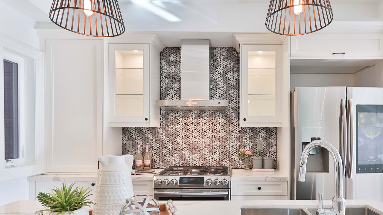 White kitchen cabinets paired with a bold floral black and white backsplash and modern stainless steel appliances. White kitchen cabinets paired with a bold floral black and white backsplash and modern stainless steel appliances.