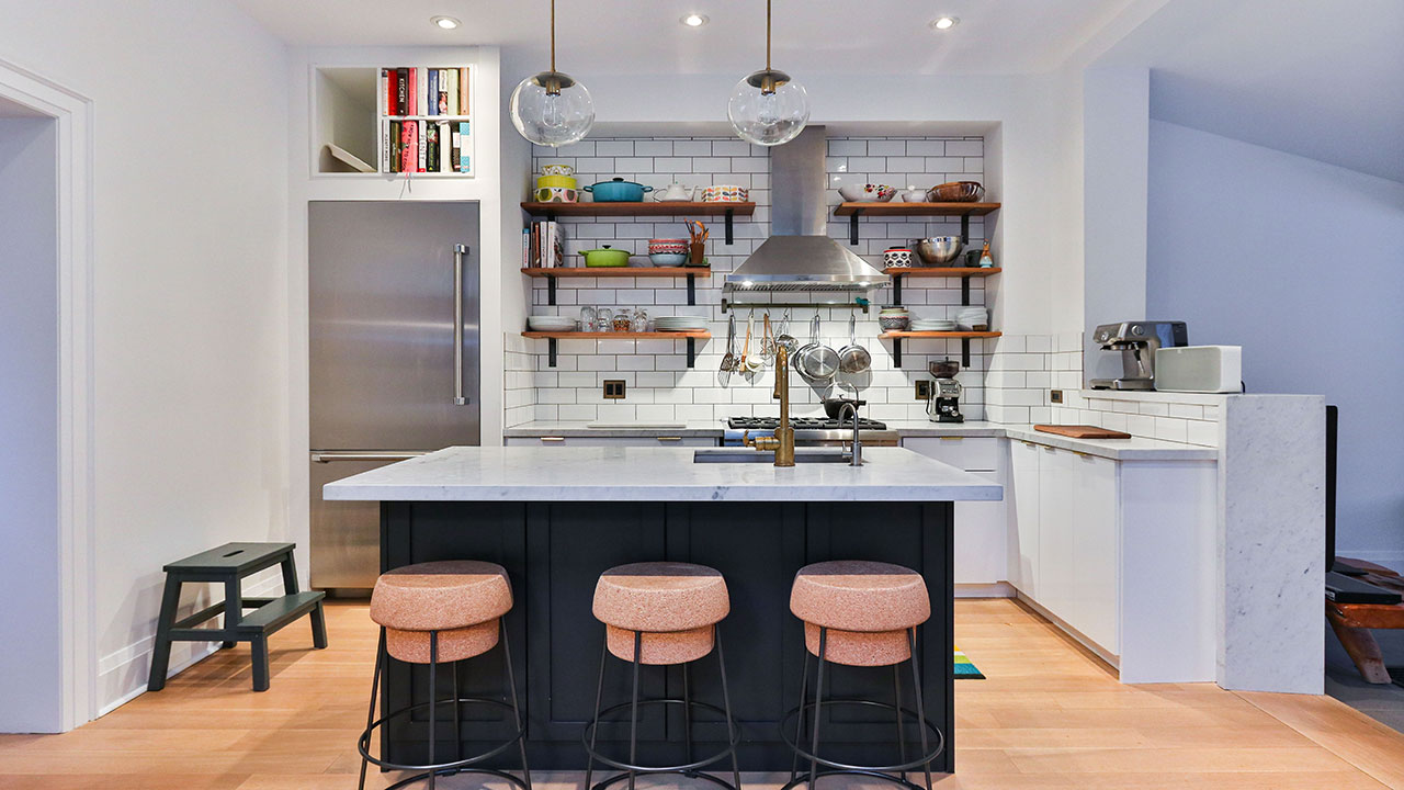Modern kitchen featuring white kitchen cabinets and open shelving with a marble island and pink bar stools. Modern kitchen featuring white kitchen cabinets and open shelving with a marble island and pink bar stools.